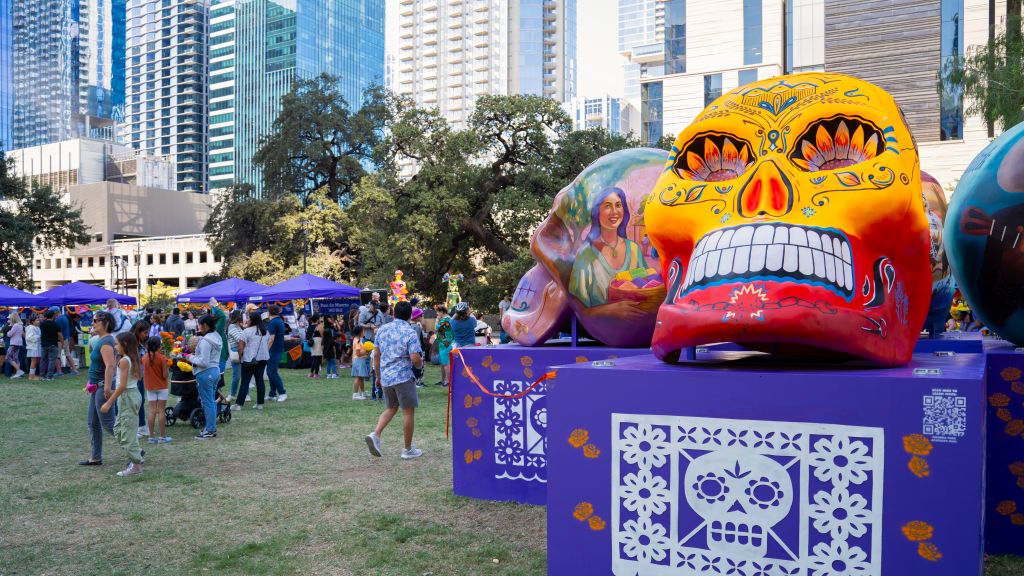 Painted skull sculptures at an urban park during an outdoor market