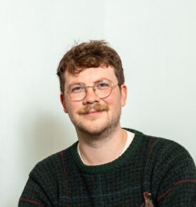 A close up portrait of a person smiling and making eye contact with the viewer