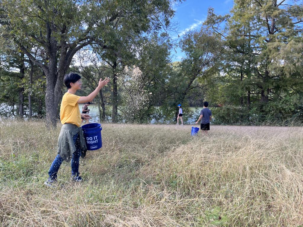 A volunteer throws a seed mix in a field