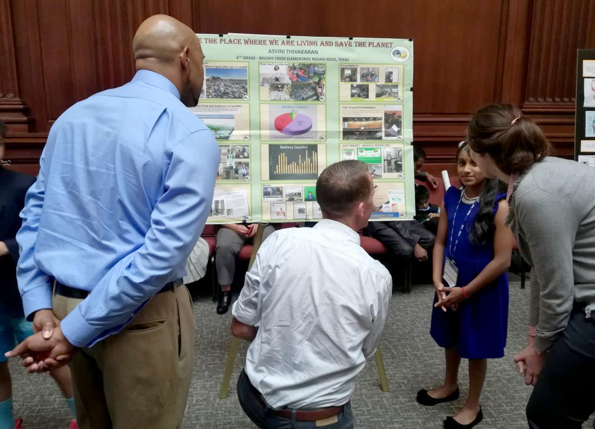 Asvini showing her project to officials on a project board.