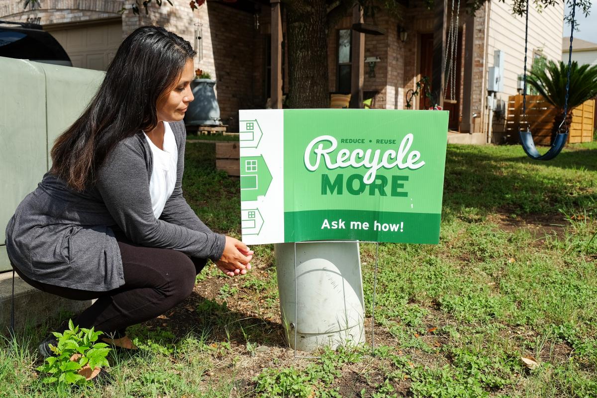 Paula in yard with sign that reads "Recycle More: ask me how!"