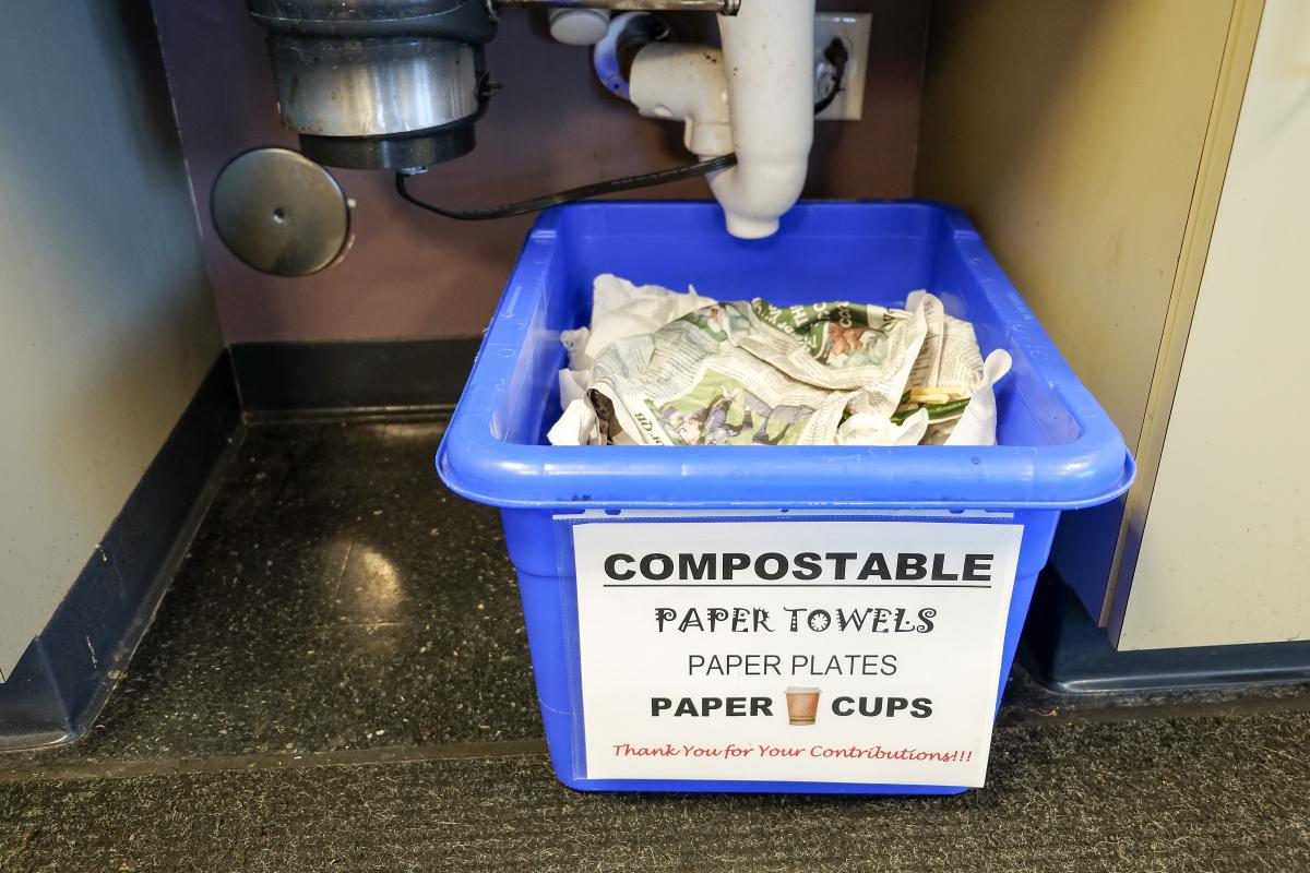 Office compost bin with sign that reads "Compostable: paper towels, paper plates, paper cups"