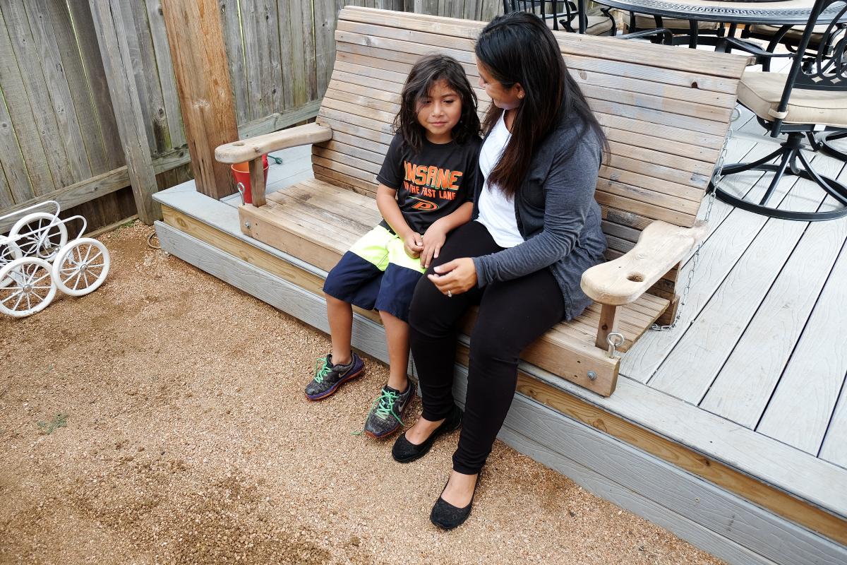 Paula and her son sitting on a wooden bench.