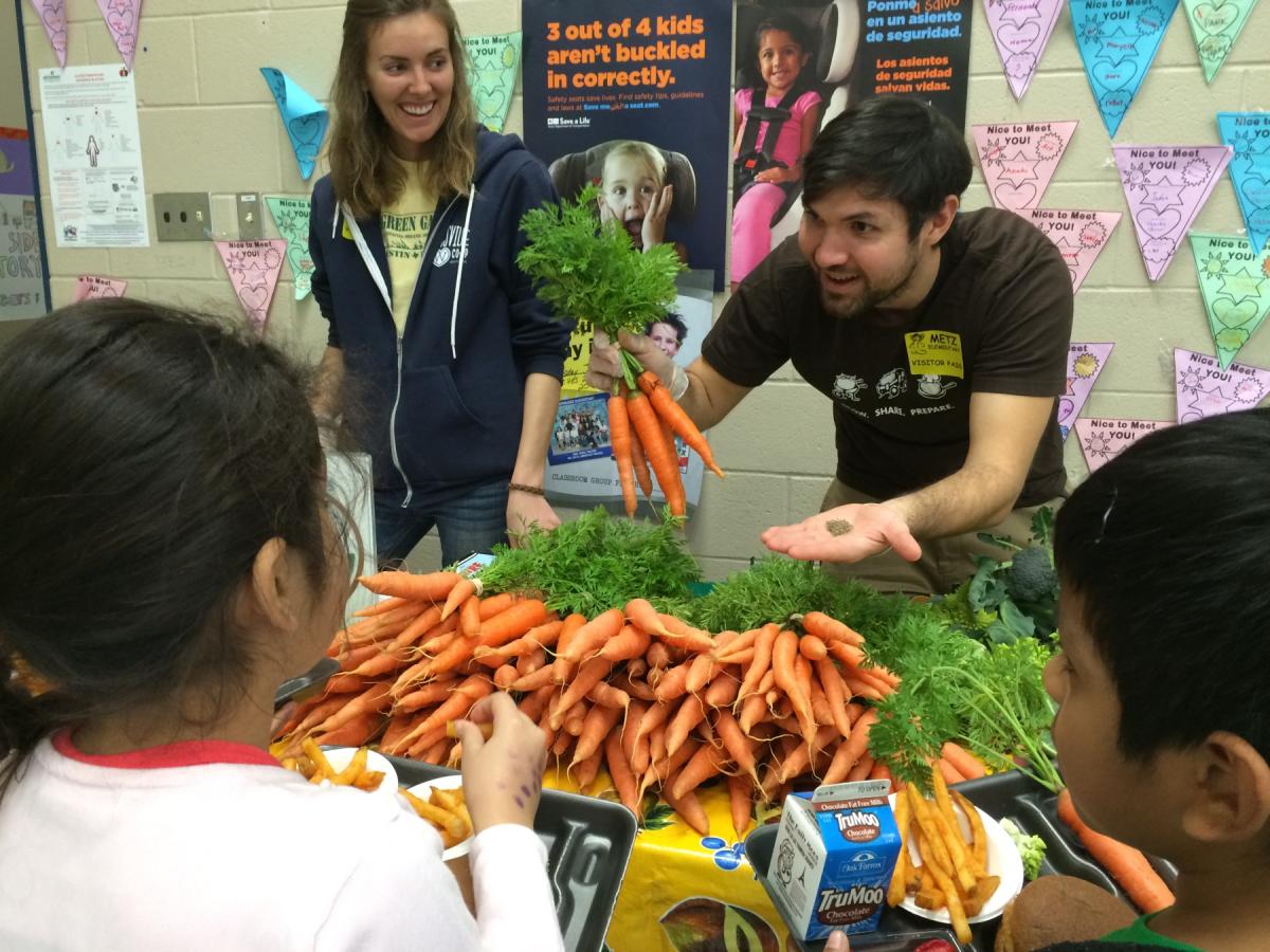 Man showing carrots to a school age kid.