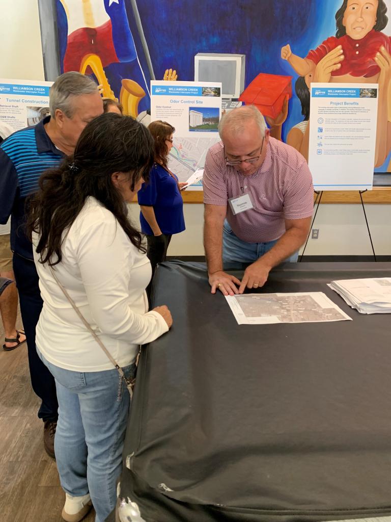 Photo from public meeting: staff and residents looking at project plans on a table