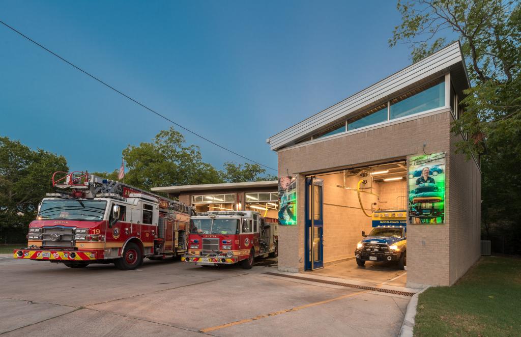A picture of a fire station with 2 firetrucks and 1 ambulance.