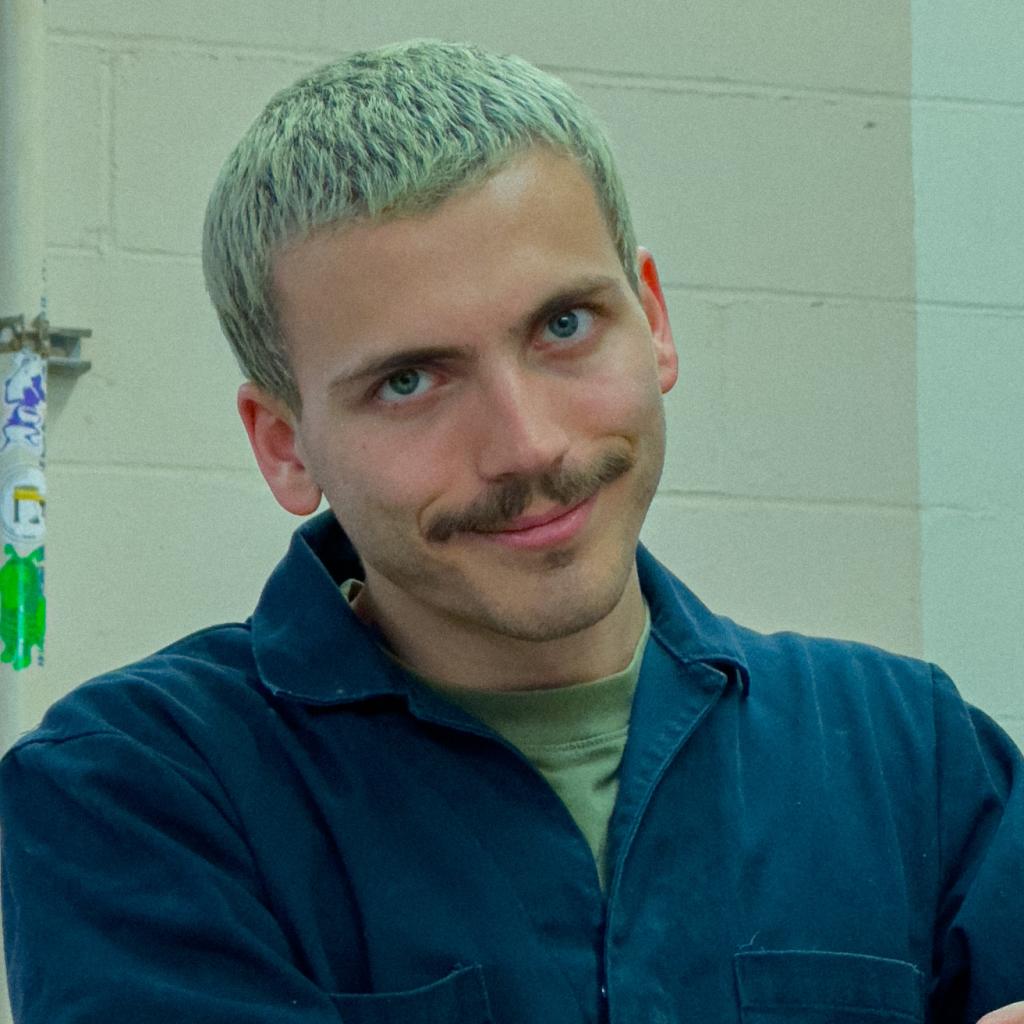 A close up portrait of a person smiling and making eye contact with the viewer