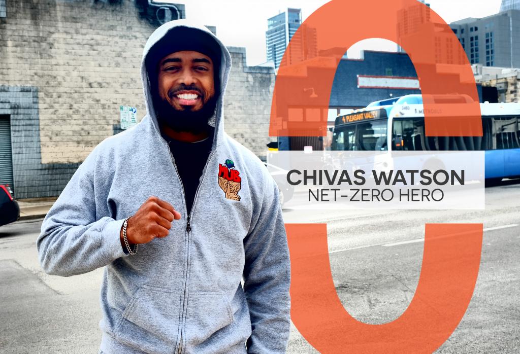 Chivas Watson smiles and holds a fist up downtown. A MetroBus is in the background.