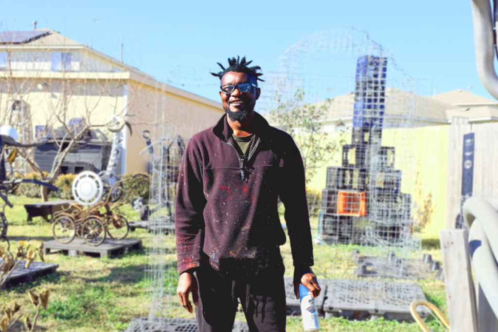 A photo of Olaniyi surrounded by sculptures he has made from repurposed materials.