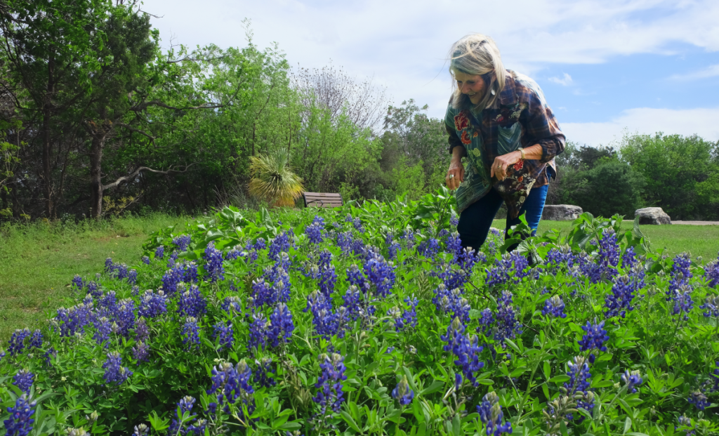 Susan leans down in a cluster of bluebonnets.