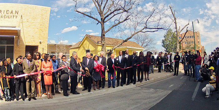 People lining up to cut a red ribbon at the grand opening of the facility.