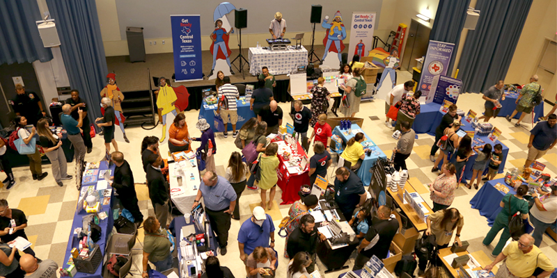 A photo showing people attending the Get Ready Central Texas Emergency Preparedness Fair, visiting educational booths while a DJ plays.