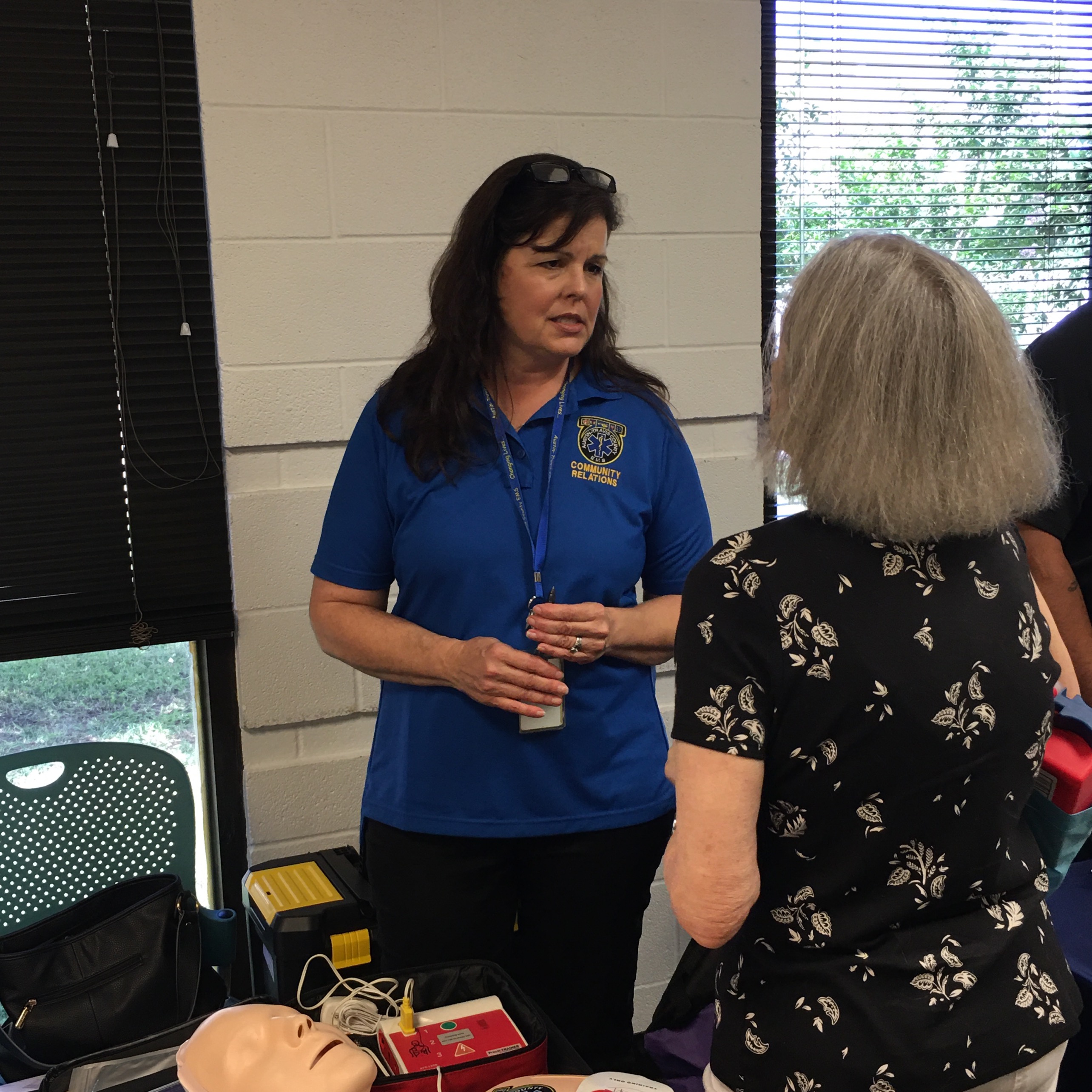 Woman speaks to an elderly woman at a presentation booth about emergency preparedness.