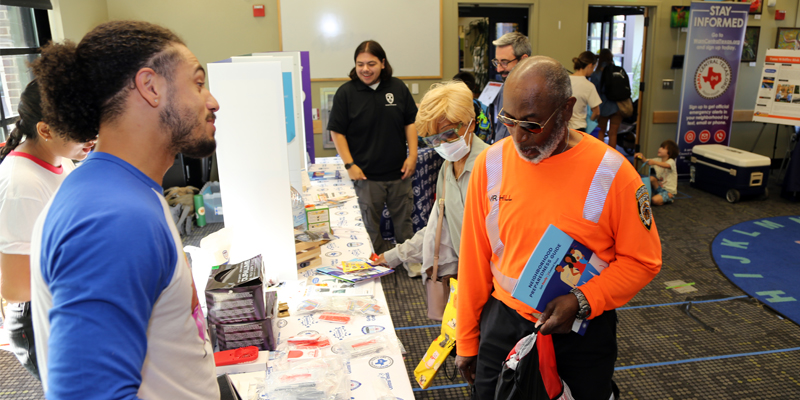 A photo showing community members visiting a preparedness booth at a pop-up event at a library.