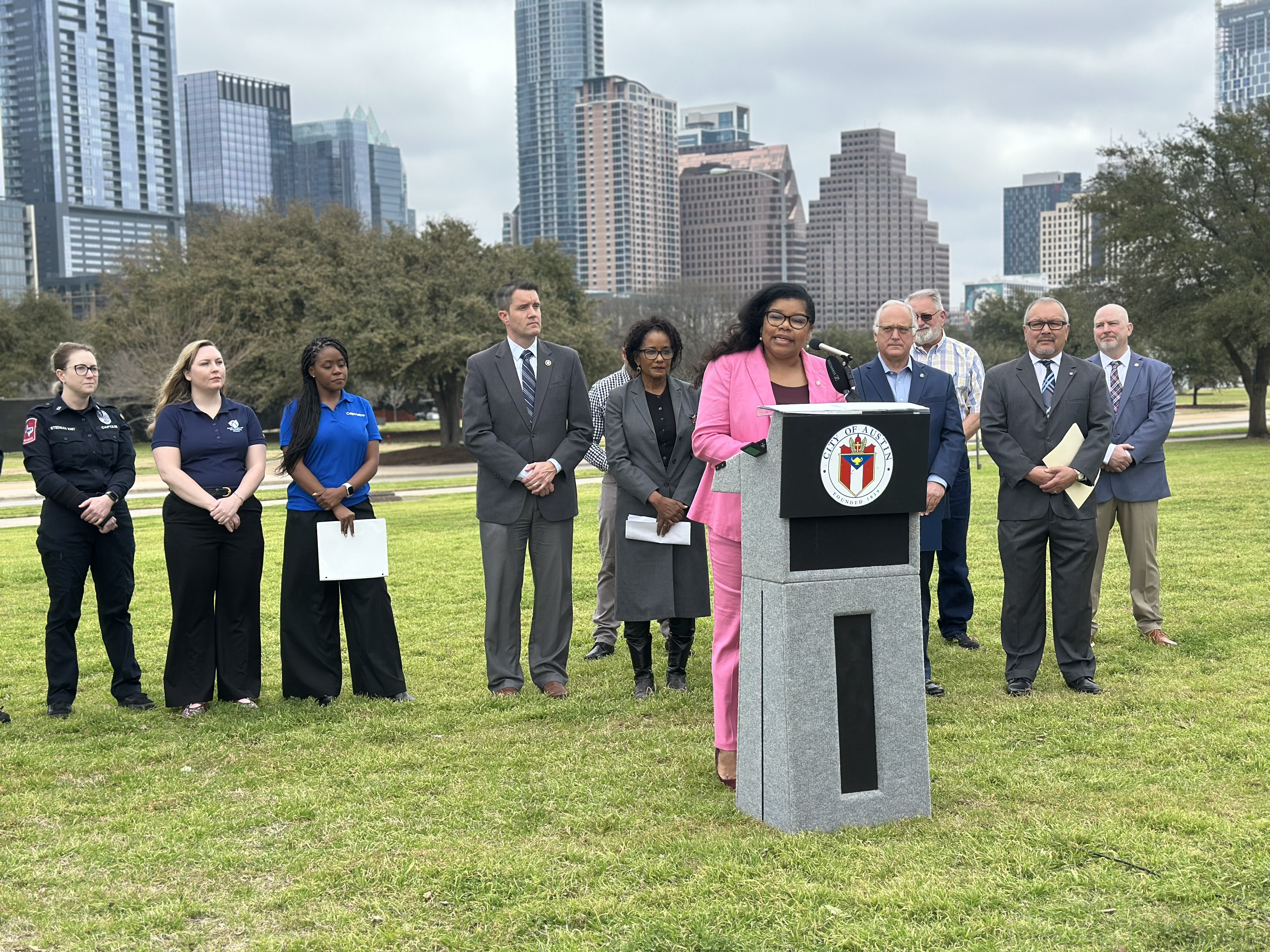 Press conference in park with city skyline in the background