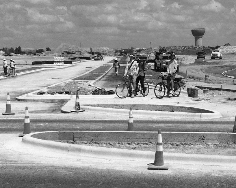 Caption: City bikeway design staff checking on construction of a protected intersection and a planted median separated two-way protected bicycle lanes on Tilley Street in the Mueller Redevelopment.