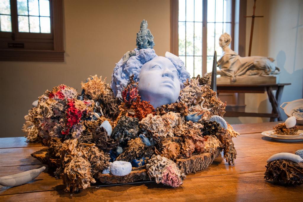 sculpture of a womans head surrounded by dried flowers