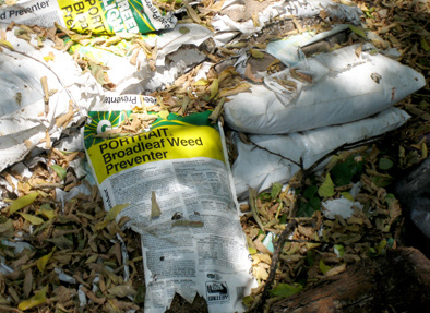 Improper disposal of herbicide (weed killer) on the ground adjacent to an alleyway.