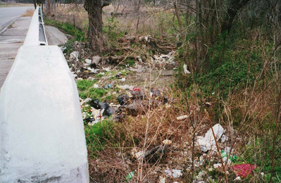 Bags of trash dumped in a creek from a residence.