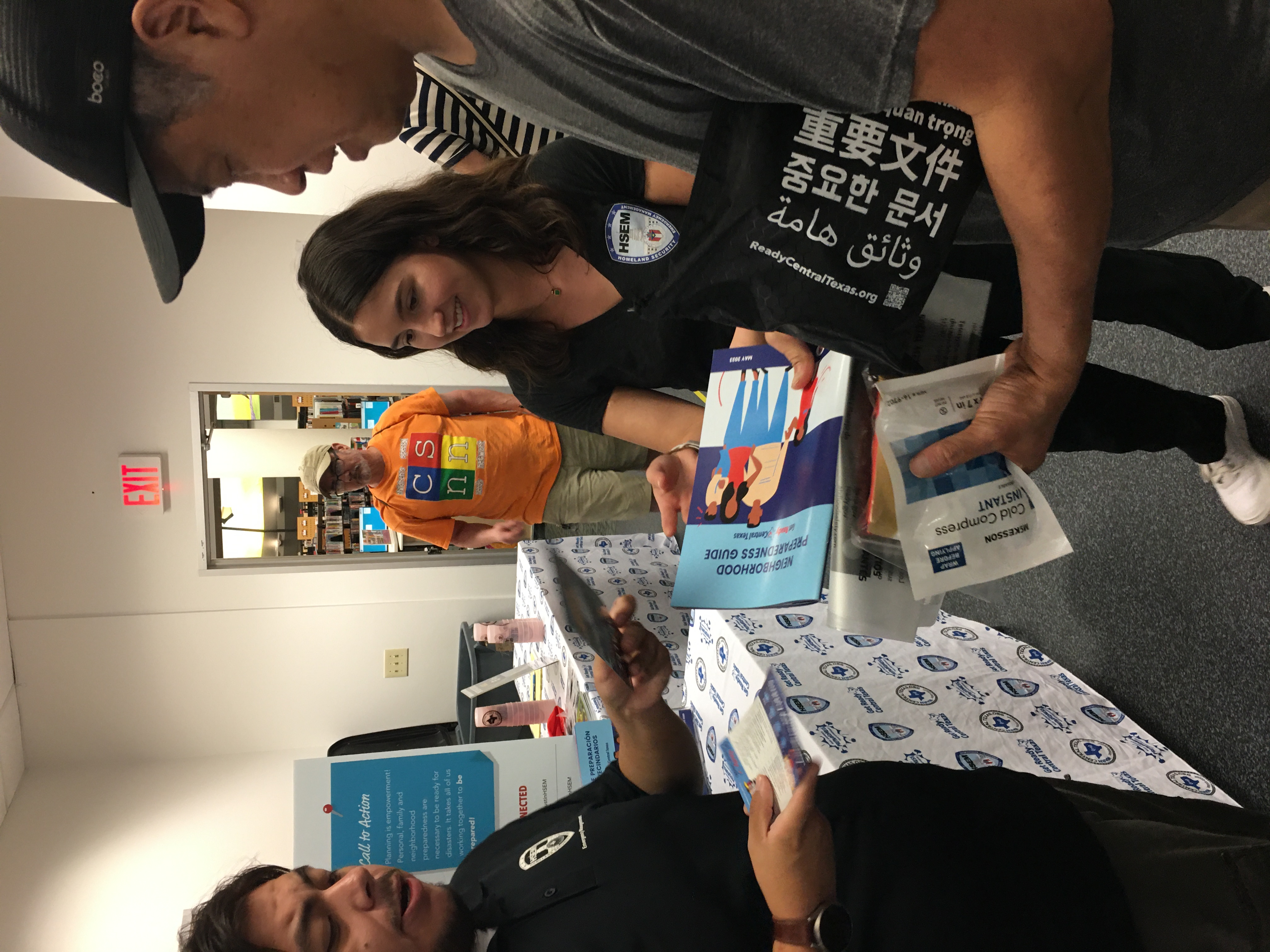 An Hispanic man and women discuss emergency preparedness with an Asian man.