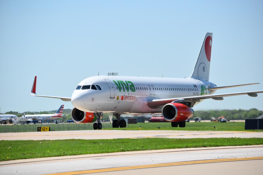 An airplane that saus Viva in green and aerobus in red. The plane is on the ground.