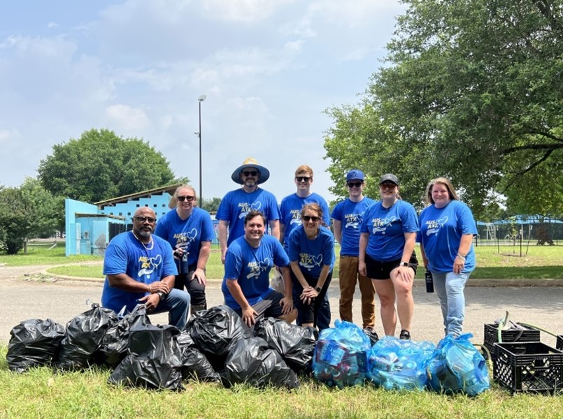 People around trash bags smiling for camera.