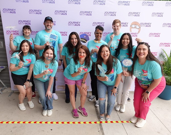 A group of people smiling at the camera holding up props.