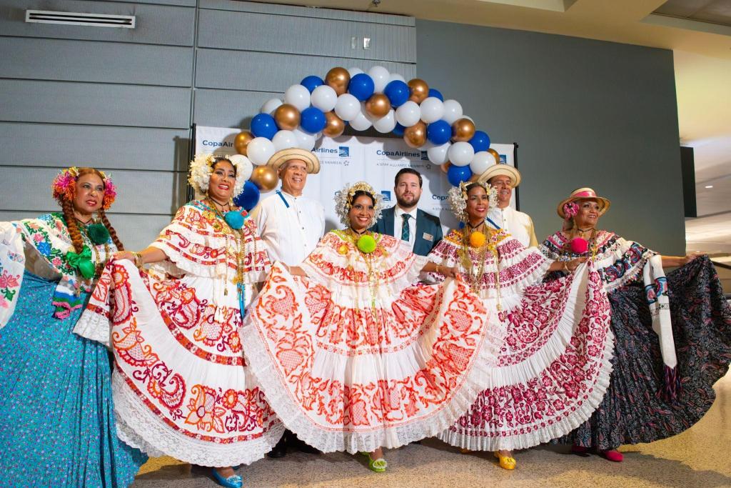 Panamianian dancers showing thier dresses off in front of a Copa Airlines banner