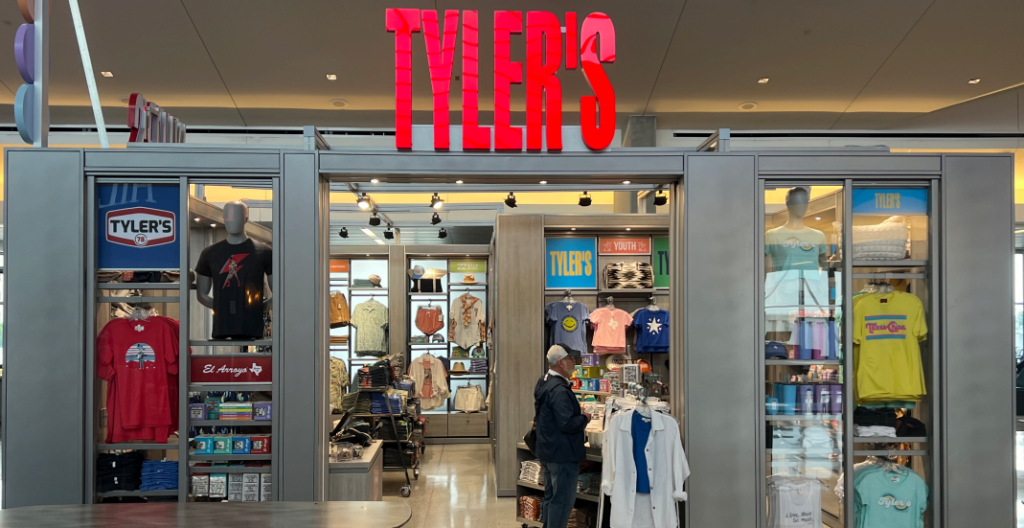 A storefront that says Tyler's in red and shirts and stuff for sell.