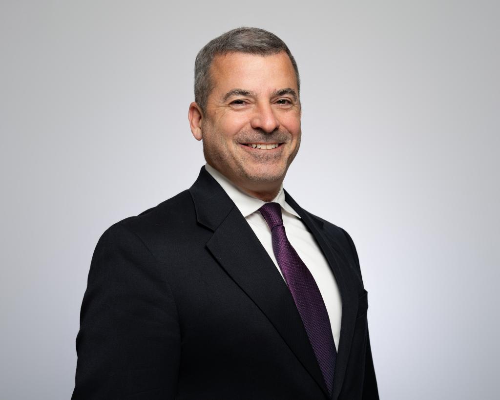 Headshot of man in suit and tie smiling