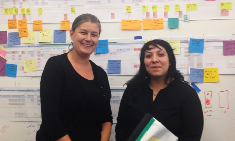 Photo of Ashley Fisher and Alba Sereno in front of a colorful whiteboard