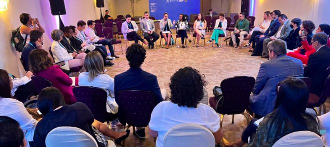 Photograph of a group of people seated in a large circle