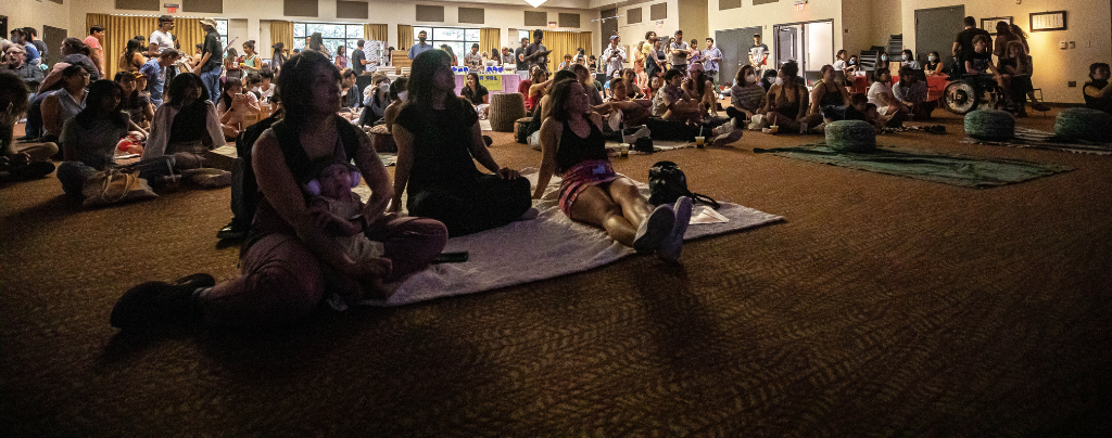 people sit on blankets on the floor in the AARC ballroom to enjoy performances from the Tones music series