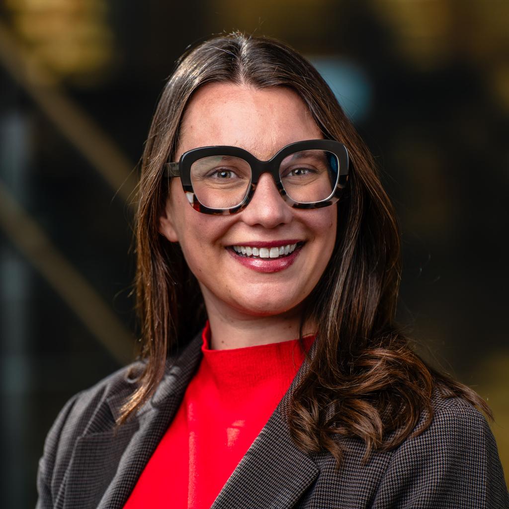  A close up photographic portrait of a person making eye contact and smiling at the viewer