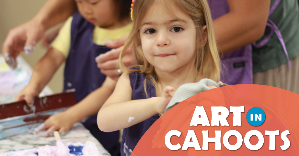 A photograph of two children creating shaving cream art one is in action and the other is paused and staring at the viewer. Also the text 'Art In Cahoots'