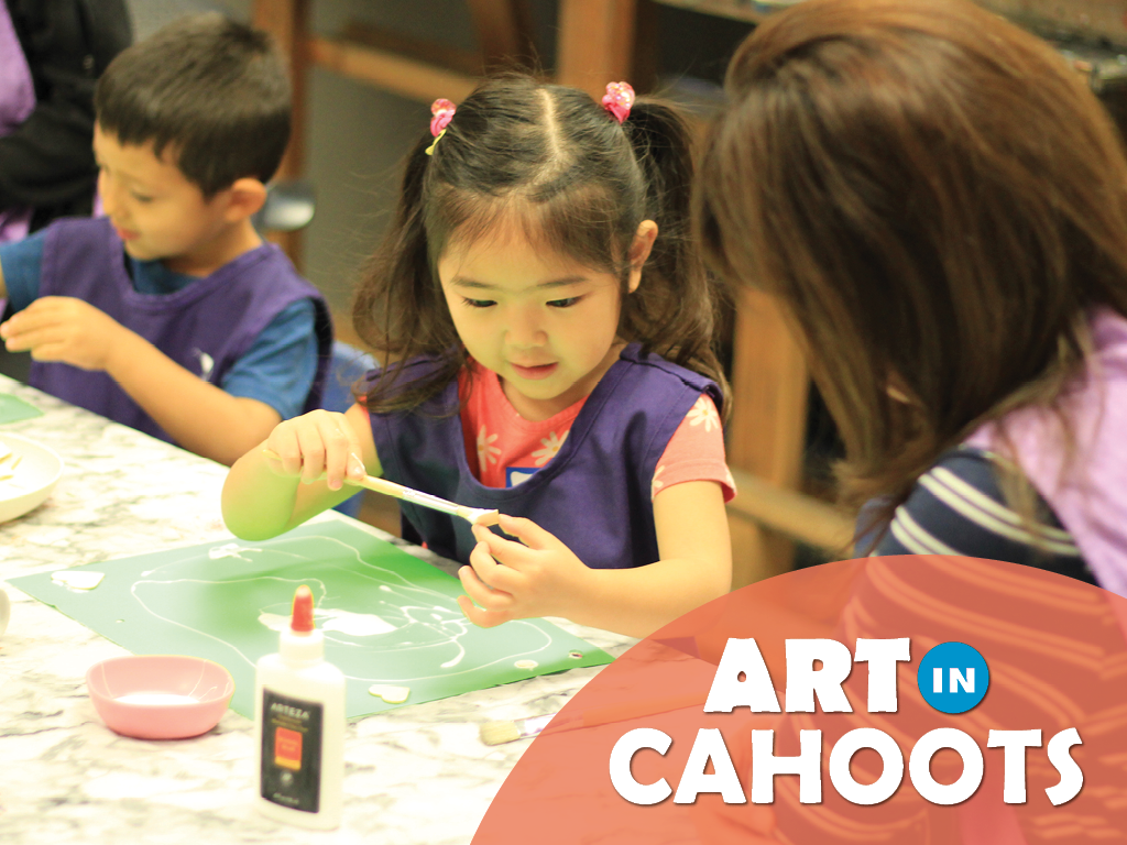 An image of two children sitting at a table gluing a collage of items onto paper and the text 'Art In Cahoots'