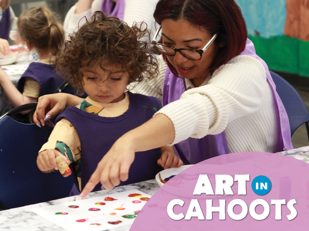 An image of a child and adult working together on a painting created by a stamp pressed in paint with the text 'Art In Cahoots'