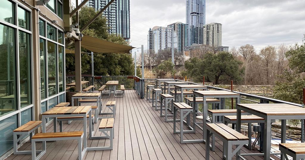 Image of patio at Waller Creek Boathouse showing picnic tables and buildings behind