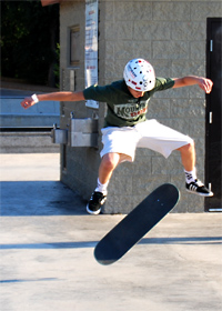 Youth jumping in the air while flipping skateboard