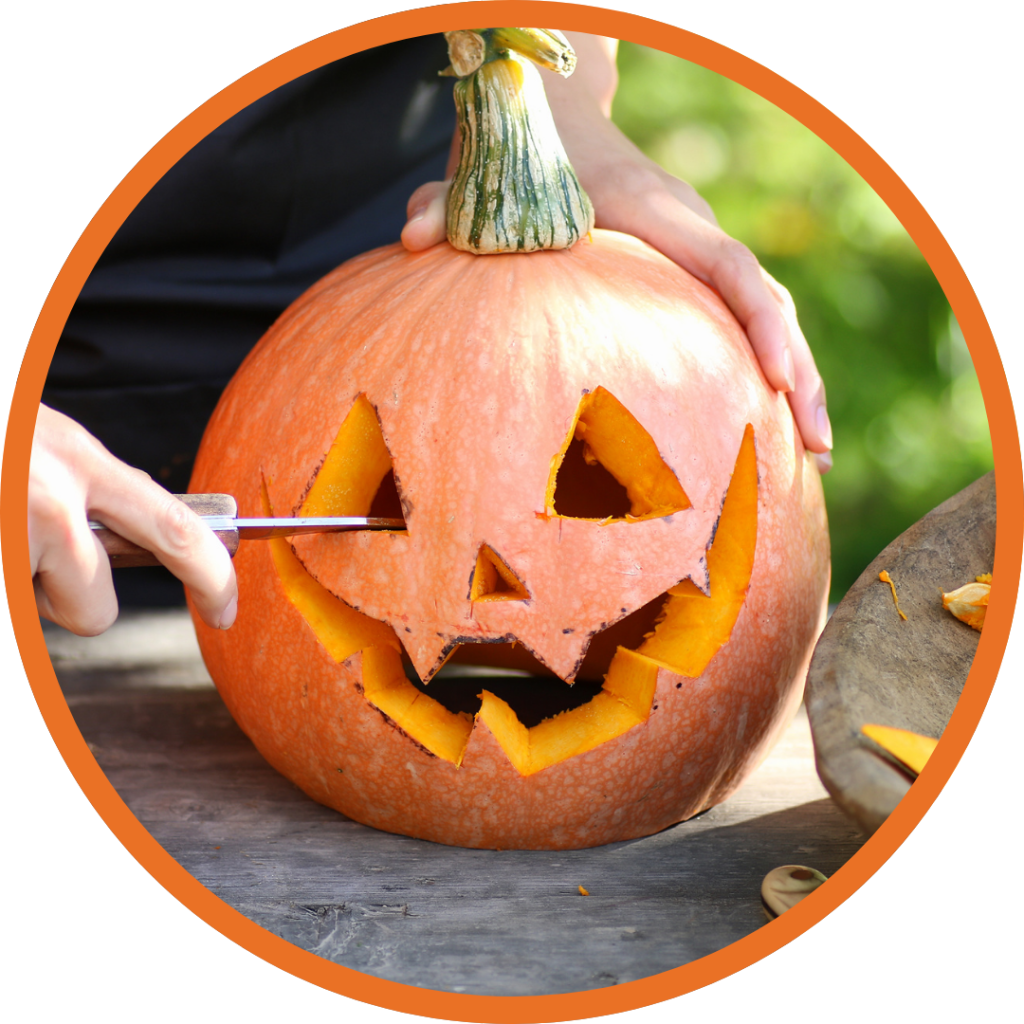 A closeup of a hand carving a pumpkin.