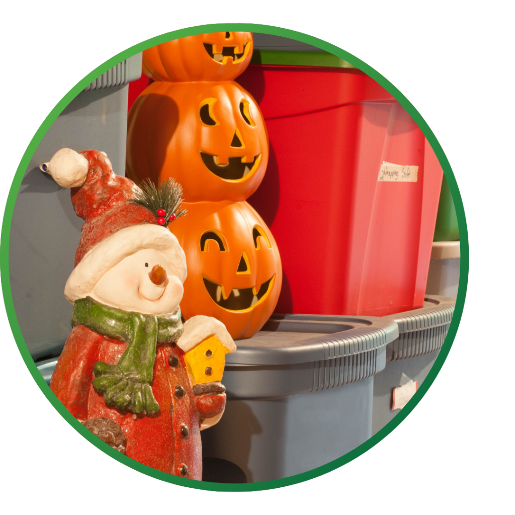 Winter and Halloween decorations stacked with bins in a storage area.