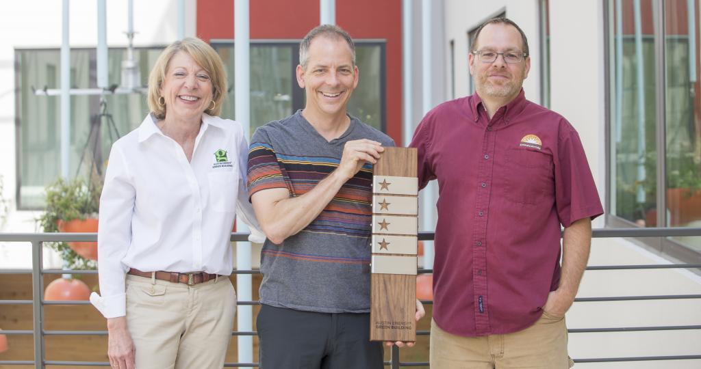 Walter Moreau standing next to two people holding a four-star award.