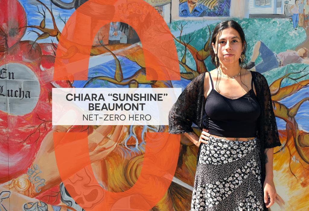 Chiara "Sunshine" Beaumont stands in front of a mural at Red Salmon Arts. Text reads, "Chiara 'Sunshine' Beaumont: Net-Zero Hero."