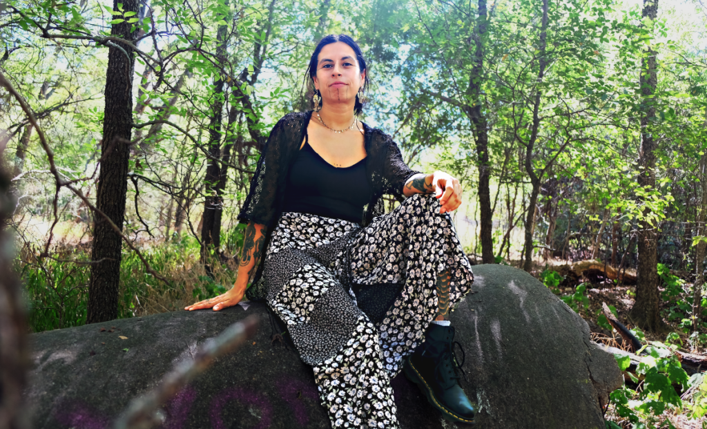 Chiara sits on a cement structure surrounded by trees.