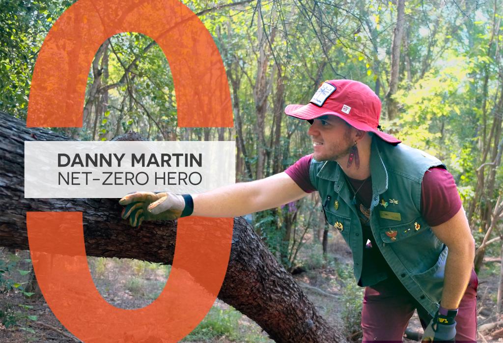 Danny Martin points towards a tree branch. He wears a green vest with pins scattered across it. Text reads, "Danny Martin: Net-Zero Hero."