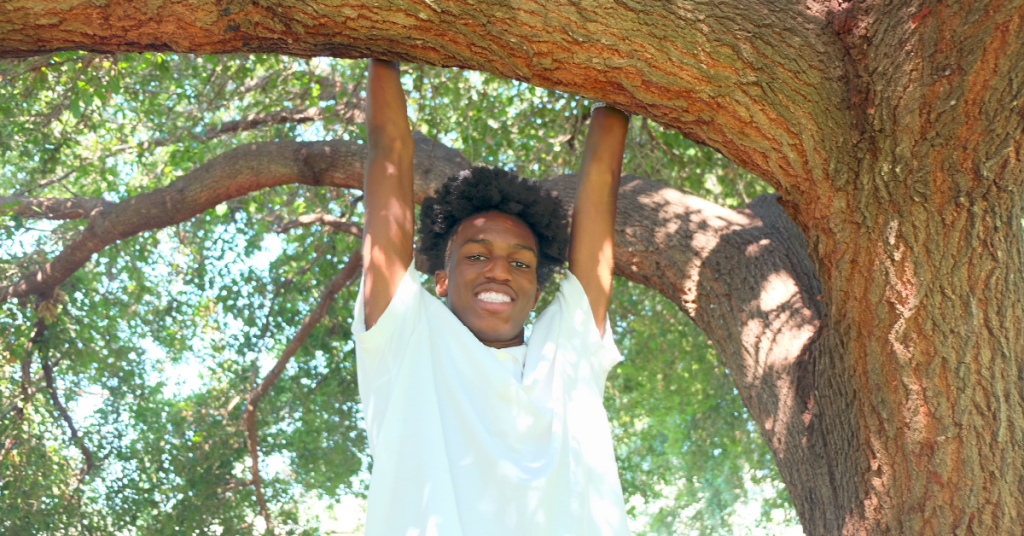 Elijah holds onto a large tree branch.