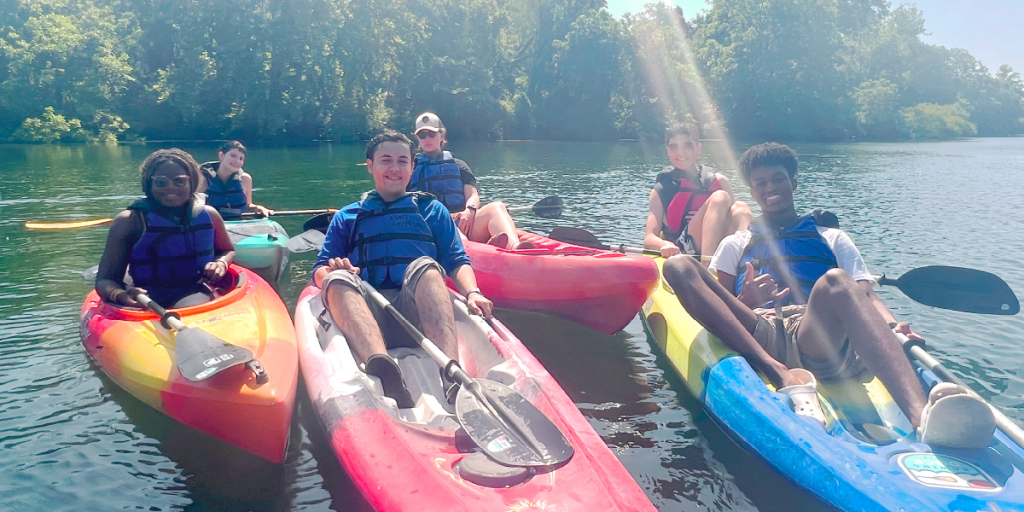 Six young people sit in colorful kayak on Ladybird Lake.