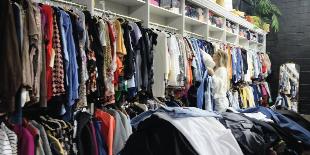 Kelley sorts clothes into the shelves at Heartening.