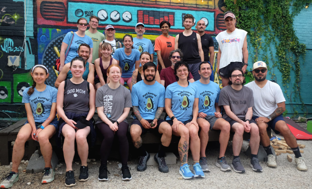 A group photo of the Plant Powered Athlete ATX running club in front of a colorful mural at the Vegan Nom food truck park.