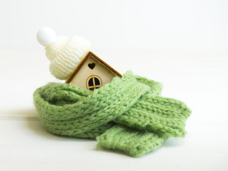 small wooden house wrapped in a green scarf with a white hat